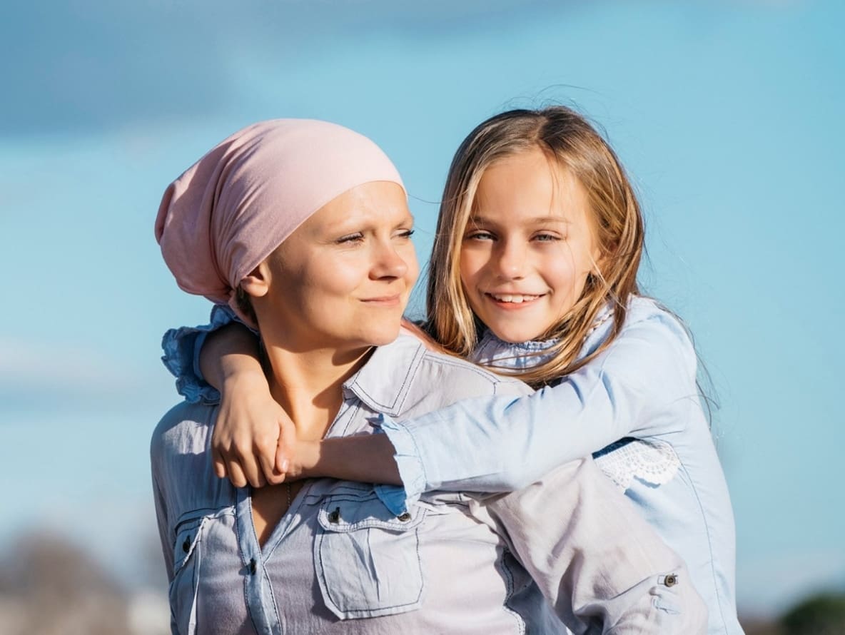 A woman in a bandana carrying a young girl on her back with ease
